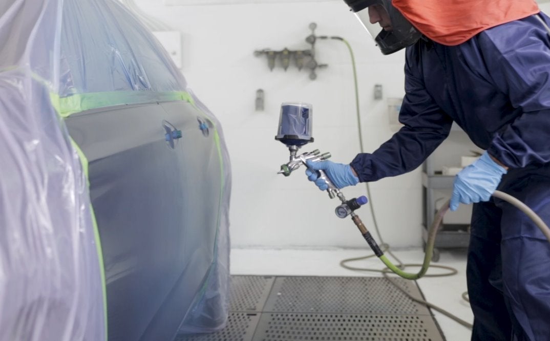 trabajador pintando un auto